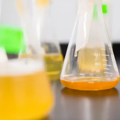 Scientific beakers filled with various yellow and orange liquids.